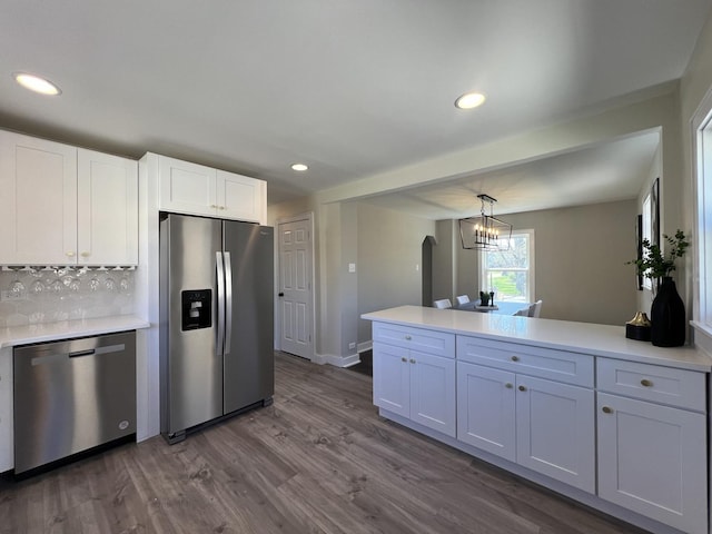 kitchen with recessed lighting, a peninsula, dark wood-style floors, and appliances with stainless steel finishes
