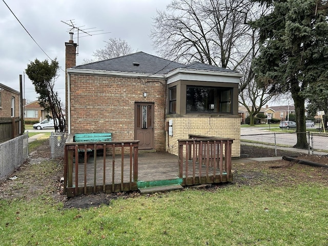 back of property featuring brick siding, fence, a yard, and a chimney
