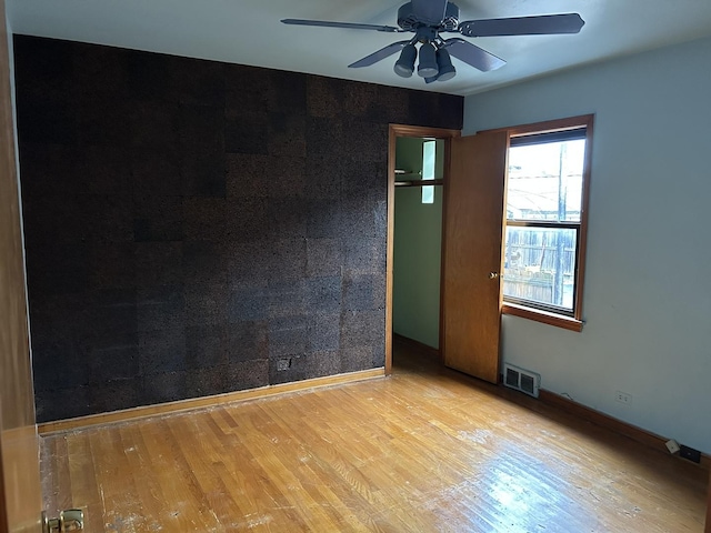 spare room with visible vents, baseboards, a ceiling fan, and wood finished floors