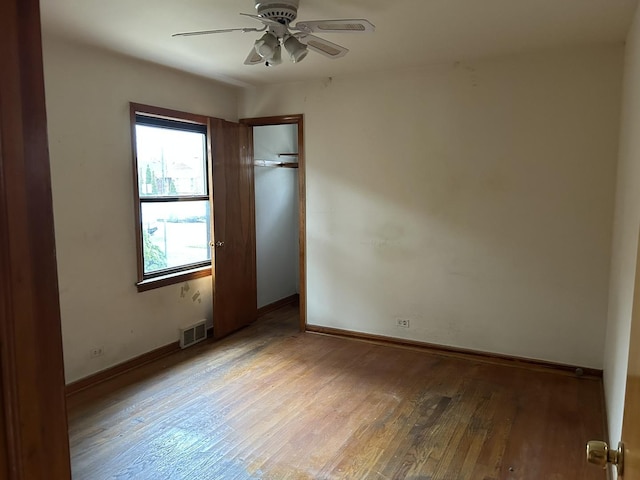 unfurnished bedroom featuring baseboards, wood-type flooring, a ceiling fan, and visible vents