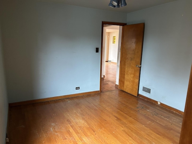 spare room featuring visible vents, baseboards, and wood finished floors