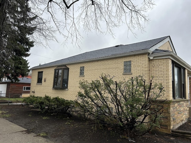 view of side of property with brick siding and fence