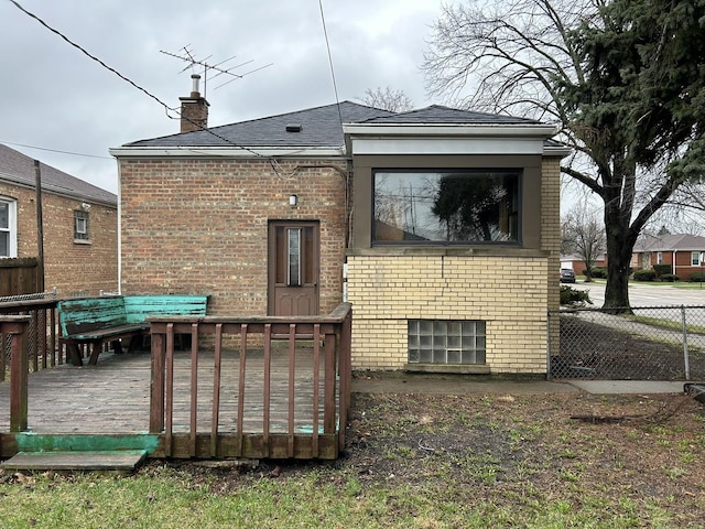 back of house featuring a chimney, a wooden deck, fence, and brick siding