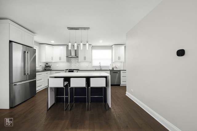 kitchen with a breakfast bar, backsplash, wall chimney exhaust hood, stainless steel appliances, and a sink