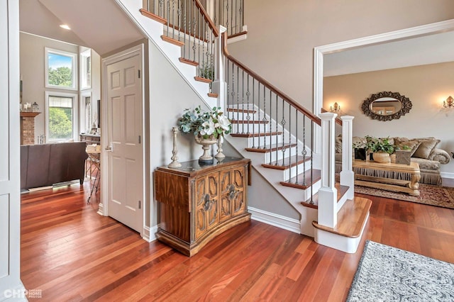 stairway featuring a high ceiling, wood finished floors, and baseboards