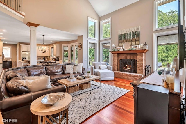 living room with high vaulted ceiling, plenty of natural light, wood finished floors, and a fireplace