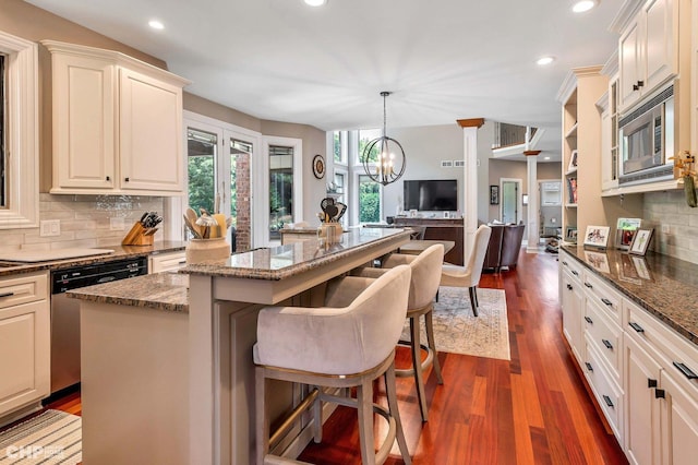 kitchen with a kitchen breakfast bar, recessed lighting, a kitchen island, dark wood finished floors, and stainless steel appliances