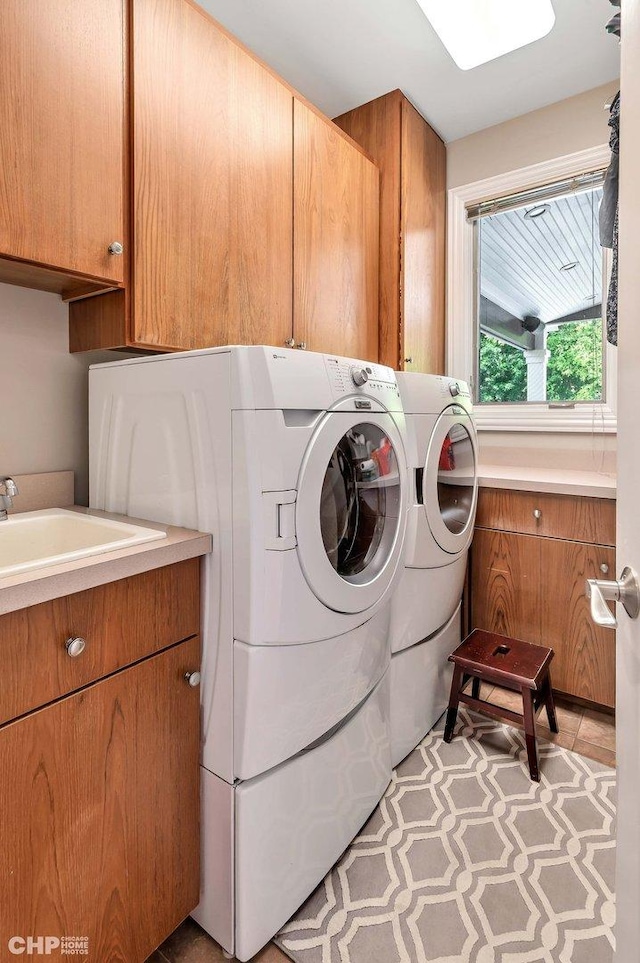 washroom with washing machine and clothes dryer, a sink, and cabinet space