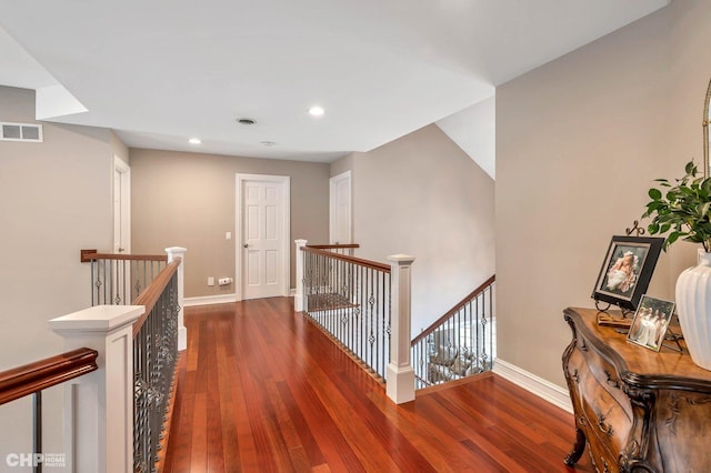 hallway featuring visible vents, baseboards, an upstairs landing, hardwood / wood-style flooring, and recessed lighting
