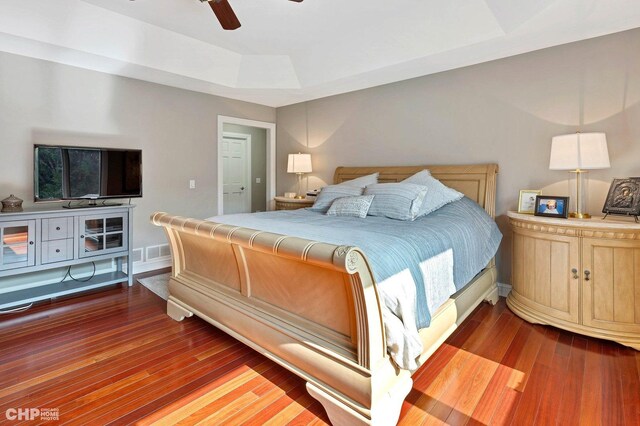 bedroom featuring a raised ceiling, wood finished floors, ceiling fan, and baseboards