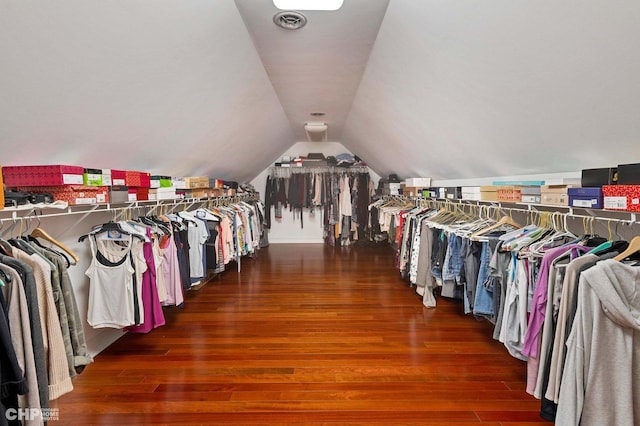 walk in closet featuring wood finished floors, visible vents, and vaulted ceiling