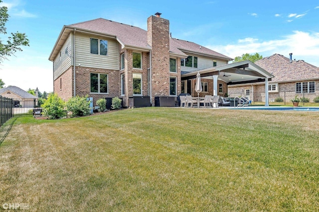 back of property featuring a yard, a patio, fence, brick siding, and a chimney