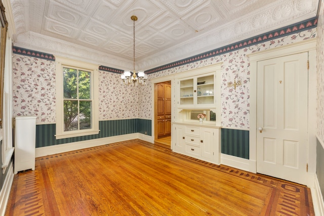 203 High St, West Chicago, IL 60185 - empty room with wallpapered walls, a chandelier, light wood-type flooring, an ornate ceiling, and wainscoting