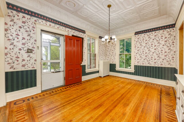 203 High St, West Chicago, IL 60185 - unfurnished dining area with wallpapered walls, a chandelier, wainscoting, wood finished floors, and an ornate ceiling