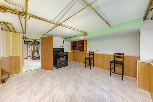 203 High St, West Chicago, IL 60185 - kitchen featuring black gas stove, a wainscoted wall, gas water heater, wooden walls, and a kitchen breakfast bar