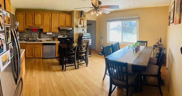 kitchen featuring brown cabinetry, a ceiling fan, appliances with stainless steel finishes, under cabinet range hood, and a sink