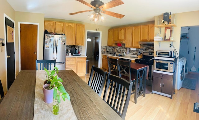 kitchen with backsplash, open shelves, under cabinet range hood, appliances with stainless steel finishes, and a sink