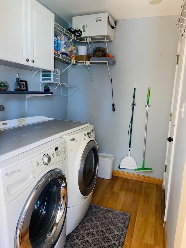 laundry room with washer and clothes dryer, wood finished floors, and cabinet space
