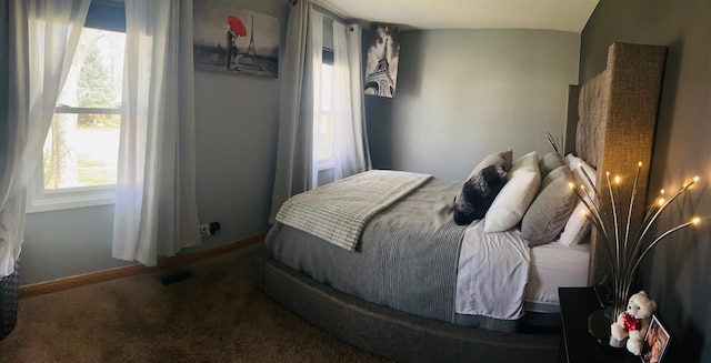 carpeted bedroom with visible vents, multiple windows, and baseboards