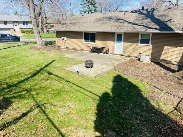 rear view of house with an outdoor fire pit, a patio, a lawn, and roof with shingles