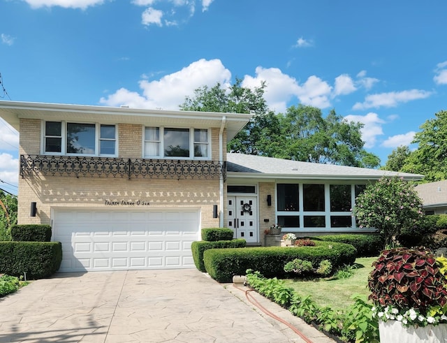 split level home with brick siding, an attached garage, and concrete driveway