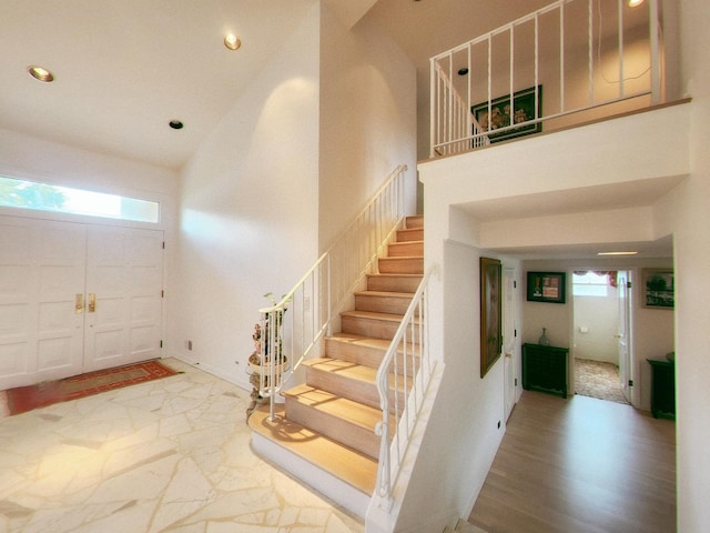 entrance foyer with a towering ceiling, recessed lighting, stairway, marble finish floor, and baseboards