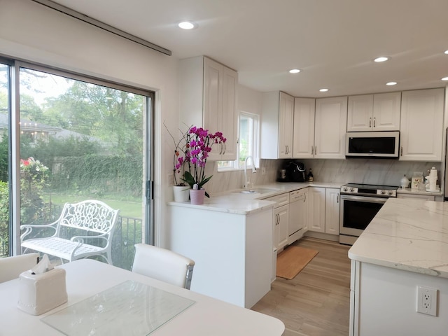 kitchen featuring backsplash, white cabinetry, a sink, and white appliances