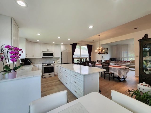 kitchen featuring tasteful backsplash, white cabinets, recessed lighting, a chandelier, and appliances with stainless steel finishes