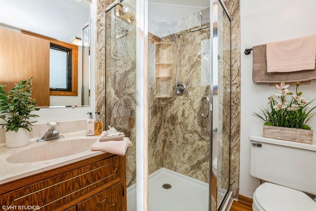 bathroom featuring a shower stall, toilet, and vanity