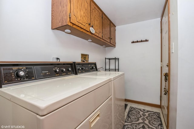 clothes washing area featuring light tile patterned floors, washing machine and clothes dryer, cabinet space, and baseboards