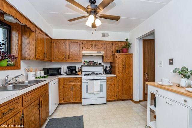 kitchen with brown cabinets, under cabinet range hood, visible vents, a sink, and white appliances