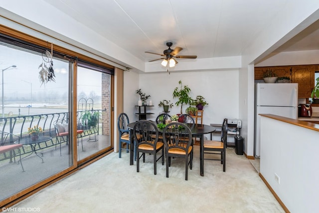 dining area featuring light carpet, baseboards, and ceiling fan