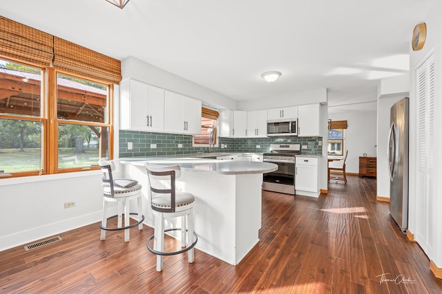kitchen with dark wood-style flooring, visible vents, a peninsula, and stainless steel appliances