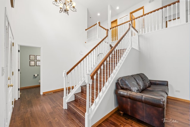 staircase with wood-type flooring, baseboards, and a notable chandelier