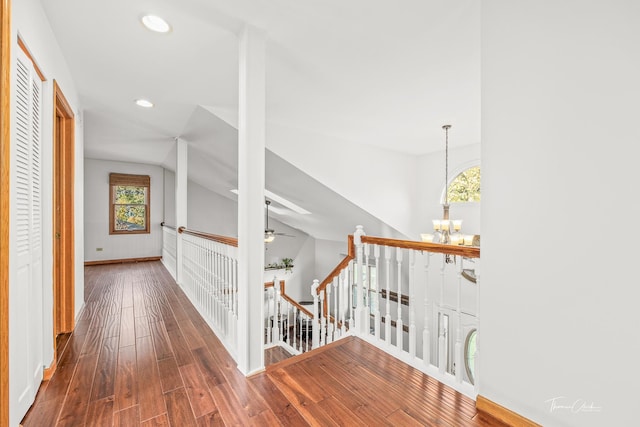 hallway with wood finished floors, vaulted ceiling, an upstairs landing, and a wealth of natural light