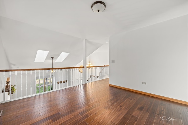 unfurnished room with a chandelier, wood finished floors, baseboards, and lofted ceiling with skylight