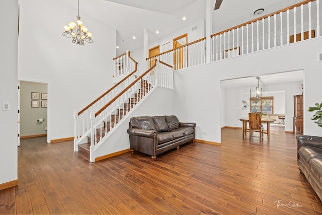 living area featuring baseboards, stairs, a high ceiling, and an inviting chandelier