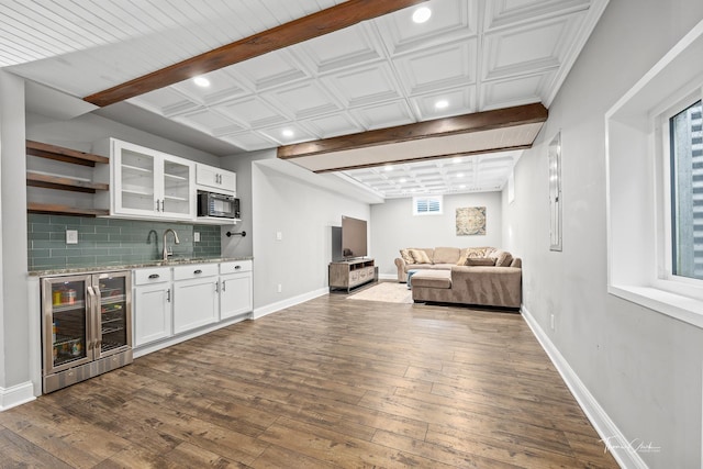 interior space featuring indoor wet bar, wine cooler, baseboards, and black microwave