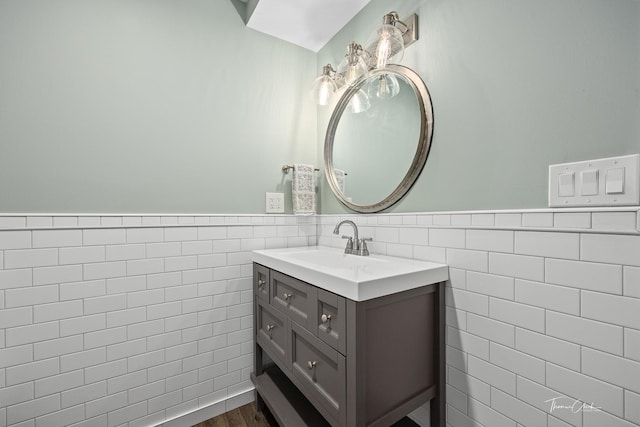 bathroom with tile walls, wood finished floors, vanity, and a wainscoted wall