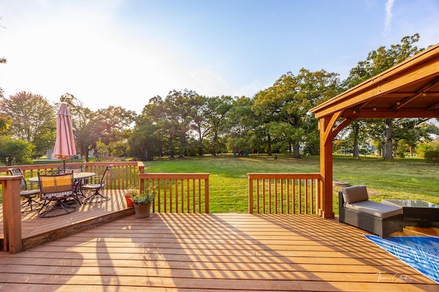 wooden terrace with outdoor dining space and a lawn