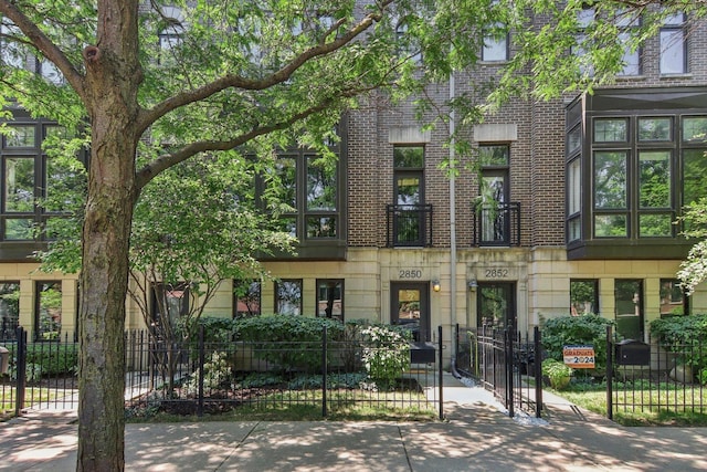 townhome / multi-family property with brick siding, a gate, and a fenced front yard