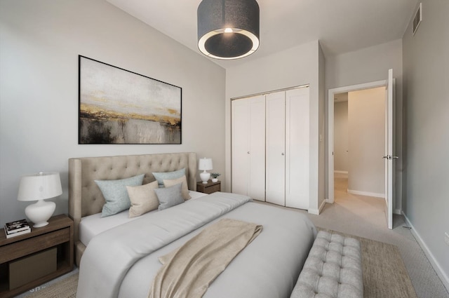 carpeted bedroom with visible vents, a closet, and baseboards