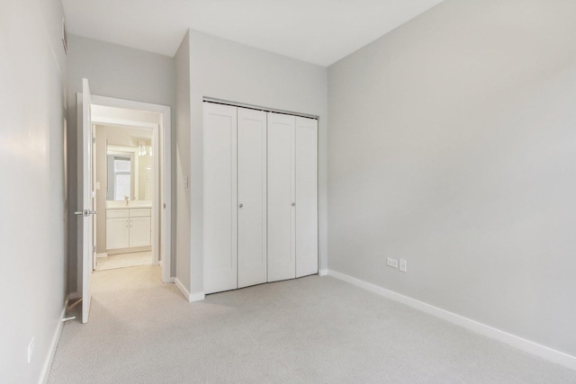unfurnished bedroom with a closet, baseboards, and light colored carpet