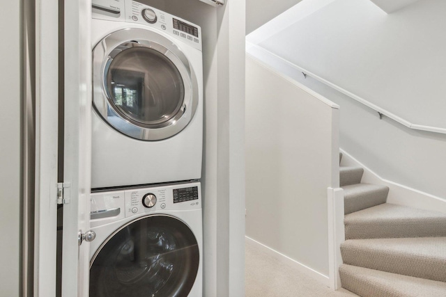 clothes washing area with carpet, stacked washer / dryer, laundry area, and baseboards