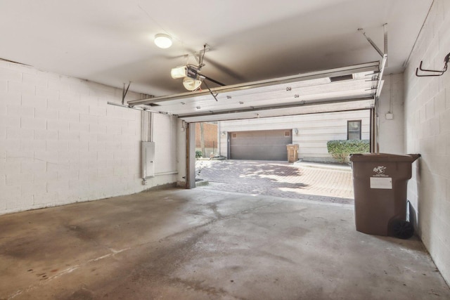 garage with a garage door opener and concrete block wall