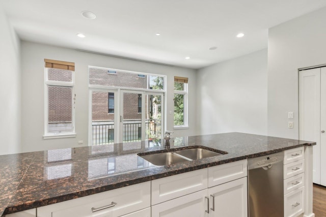 kitchen featuring white cabinets, a sink, recessed lighting, dark stone counters, and stainless steel dishwasher