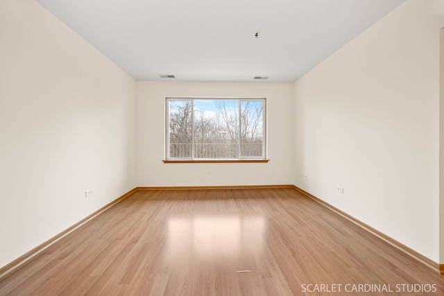 empty room with light wood-style flooring, baseboards, and visible vents