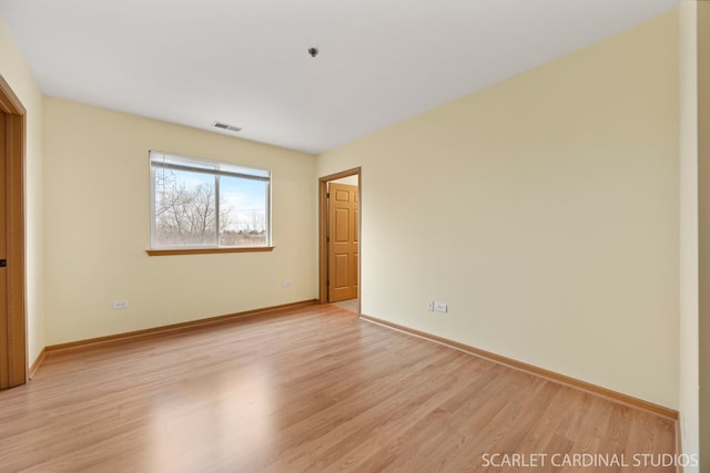 empty room featuring light wood-style floors, baseboards, and visible vents