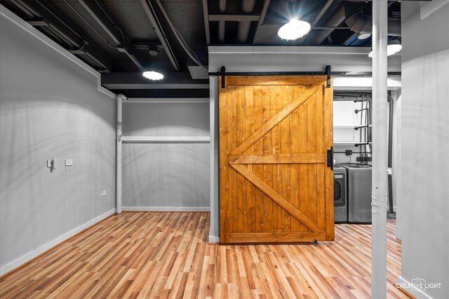 finished basement featuring washer and dryer, a barn door, baseboards, and wood finished floors