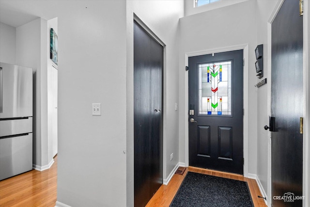 entrance foyer with light wood finished floors, a high ceiling, and baseboards